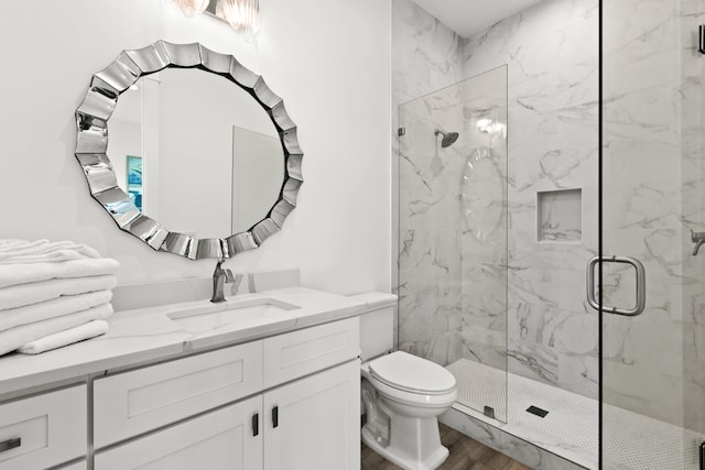 bathroom with hardwood / wood-style flooring, a shower with shower door, toilet, and vanity