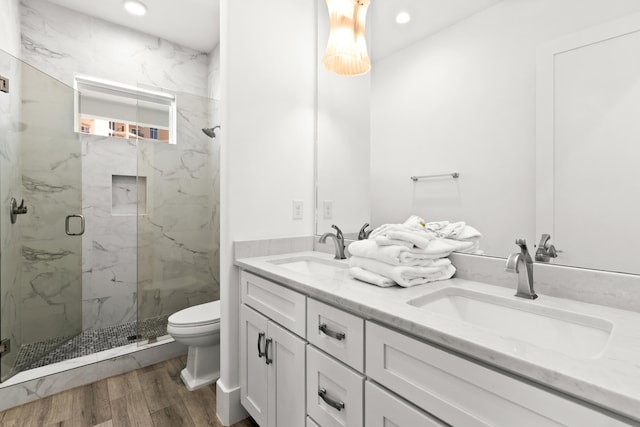 bathroom featuring walk in shower, hardwood / wood-style floors, toilet, and dual vanity