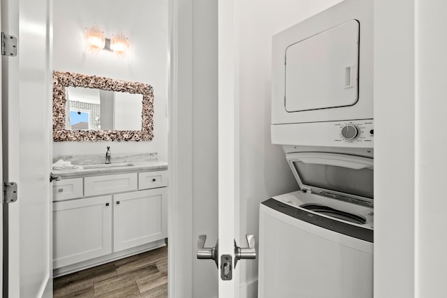 clothes washing area featuring sink, stacked washer / drying machine, and dark hardwood / wood-style floors