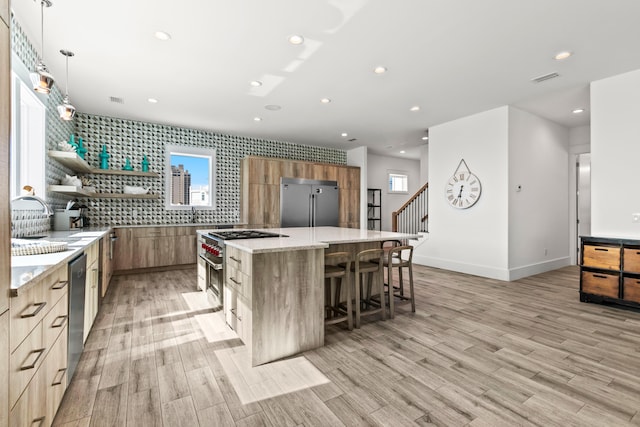 kitchen featuring a center island, premium appliances, a kitchen bar, decorative light fixtures, and light stone countertops