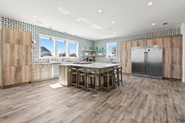 kitchen featuring a kitchen bar, light hardwood / wood-style floors, appliances with stainless steel finishes, and a center island