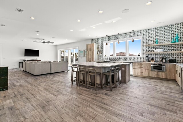 kitchen featuring a breakfast bar area, ceiling fan, tasteful backsplash, oven, and a center island