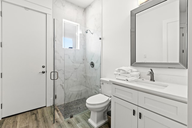 bathroom featuring hardwood / wood-style flooring, a shower with shower door, toilet, and vanity