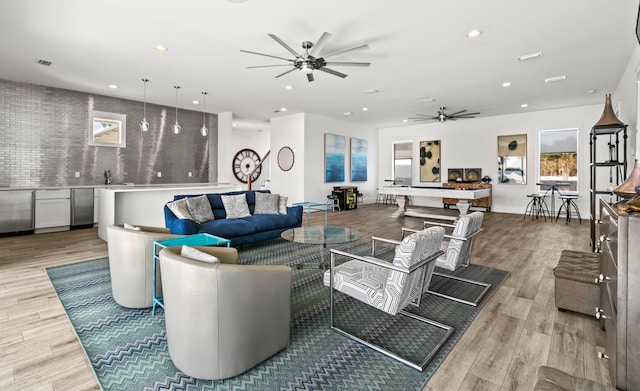 living room with ceiling fan, sink, and light wood-type flooring