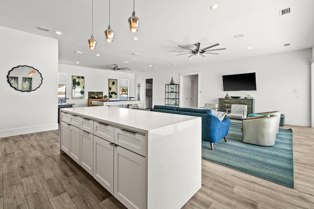 kitchen with a kitchen island, pendant lighting, white cabinets, and ceiling fan