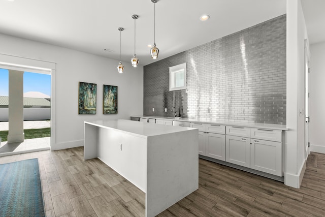 kitchen featuring a center island, tasteful backsplash, white cabinetry, hardwood / wood-style floors, and pendant lighting