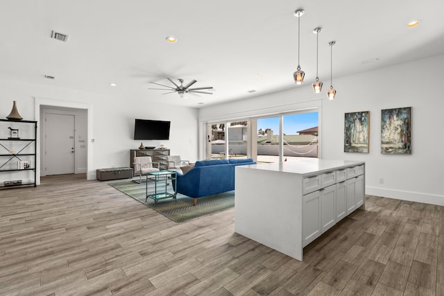 kitchen with a center island, decorative light fixtures, white cabinets, light hardwood / wood-style flooring, and ceiling fan