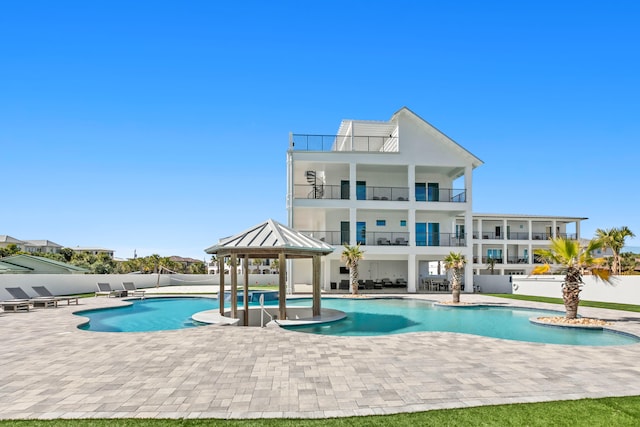 back of house featuring a fenced in pool, a patio area, and a balcony