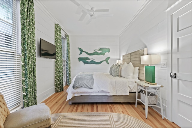 bedroom with ornamental molding, multiple windows, ceiling fan, and light wood-type flooring