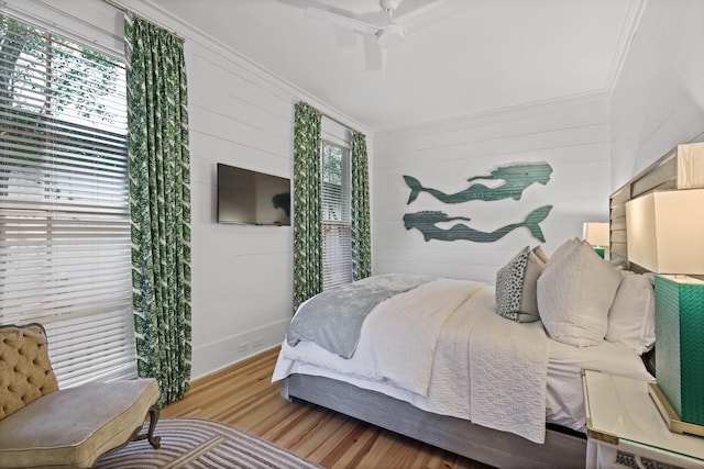 bedroom featuring light hardwood / wood-style floors, ceiling fan, and crown molding