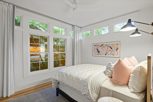 bedroom featuring dark hardwood / wood-style flooring, ceiling fan, and multiple windows