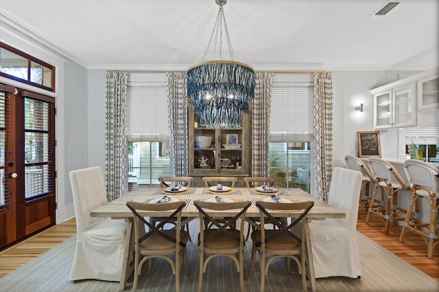 dining room with french doors, an inviting chandelier, light hardwood / wood-style flooring, and crown molding