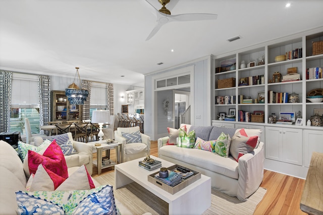 living room with light hardwood / wood-style flooring and ceiling fan with notable chandelier