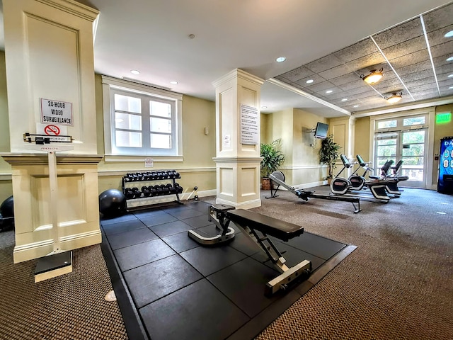 workout area featuring ornate columns and a drop ceiling