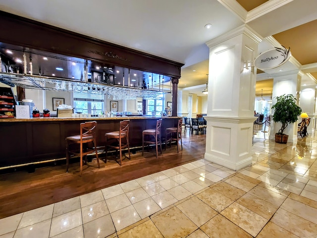 bar with ornate columns, ornamental molding, and light tile patterned flooring