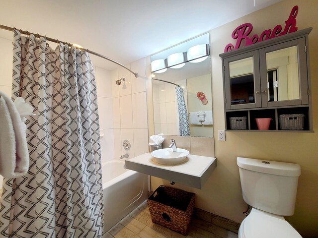 full bathroom featuring toilet, shower / bathtub combination with curtain, and sink