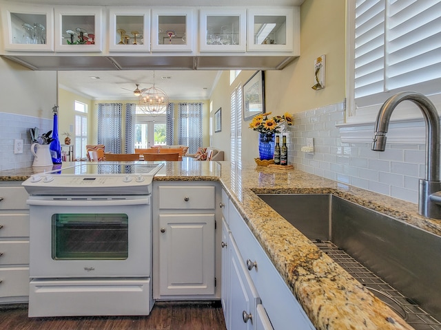 kitchen featuring dark hardwood / wood-style floors, tasteful backsplash, white electric range oven, and white cabinetry