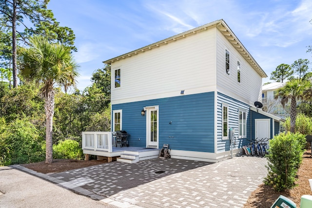 back of house featuring a wooden deck and a patio