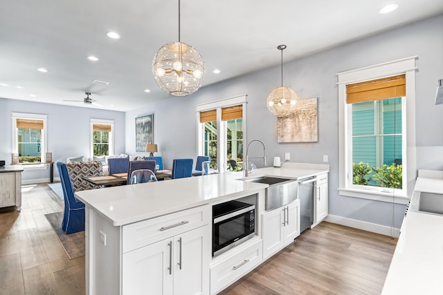 kitchen featuring decorative light fixtures, ceiling fan with notable chandelier, stainless steel appliances, light hardwood / wood-style floors, and sink