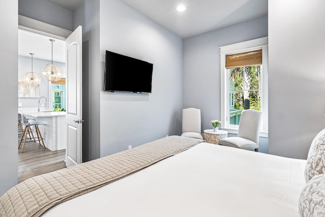 bedroom with light hardwood / wood-style flooring, an inviting chandelier, and sink