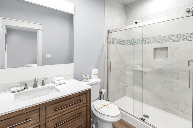 bathroom with vanity, toilet, hardwood / wood-style floors, and a shower with door