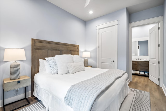 bedroom with wood-type flooring, ensuite bathroom, and sink