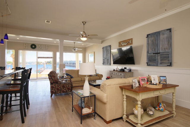 living room featuring ceiling fan, a water view, light hardwood / wood-style flooring, and crown molding