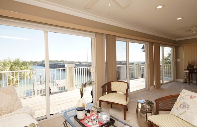 sunroom / solarium with ceiling fan and a water view