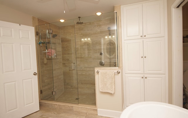 bathroom featuring hardwood / wood-style floors, ceiling fan, and a shower with door