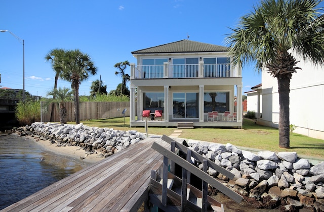 rear view of house featuring a balcony and a lawn