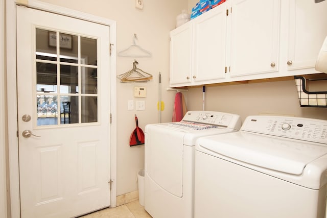 laundry area with light tile flooring, cabinets, and washer and clothes dryer