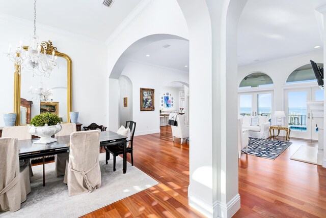 dining space with crown molding, hardwood / wood-style floors, and a notable chandelier