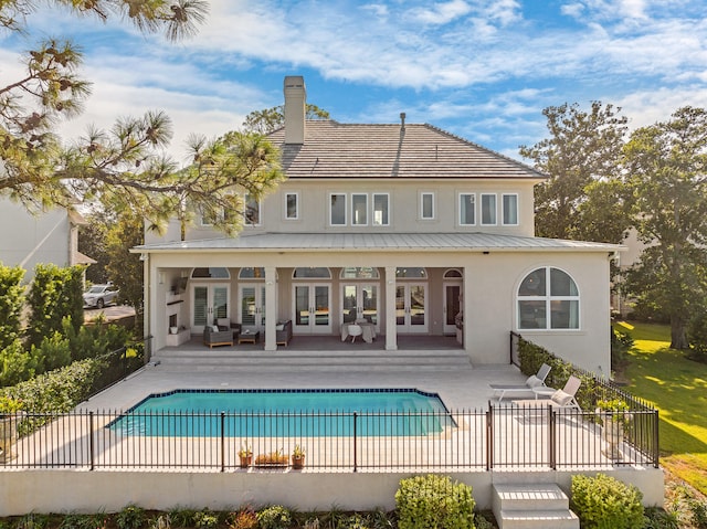 rear view of property with a fenced in pool and a patio