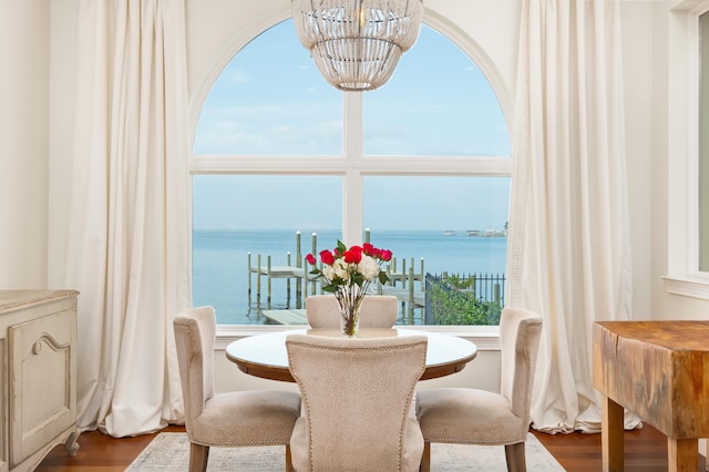 dining room with a water view, hardwood / wood-style flooring, and an inviting chandelier