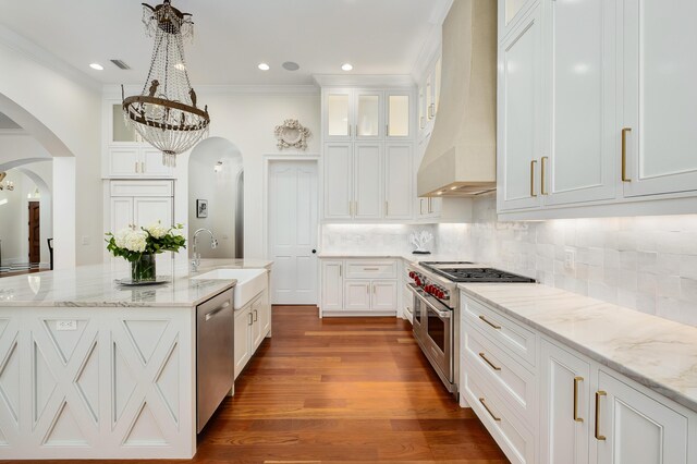 kitchen featuring appliances with stainless steel finishes, white cabinetry, wood-type flooring, and custom exhaust hood