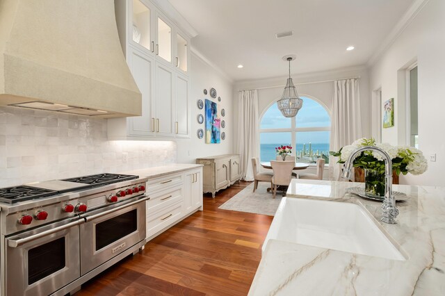 kitchen featuring range with two ovens, custom exhaust hood, hanging light fixtures, dark wood-type flooring, and white cabinets