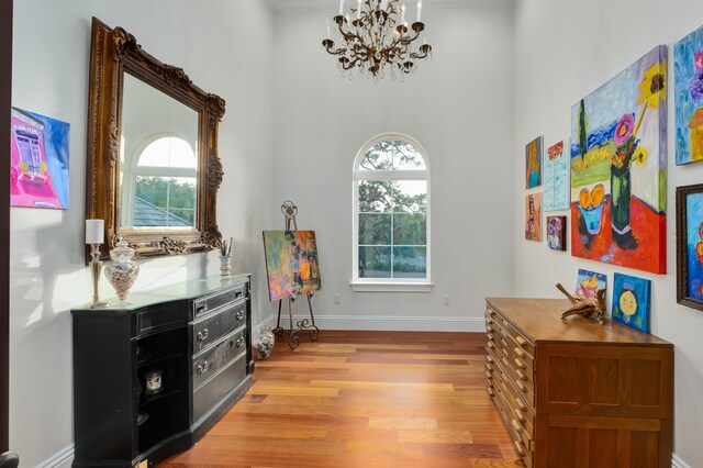 sitting room featuring plenty of natural light, a towering ceiling, light hardwood / wood-style flooring, and a chandelier