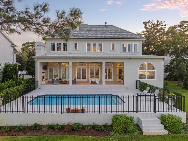 back house at dusk featuring a fenced in pool and a patio