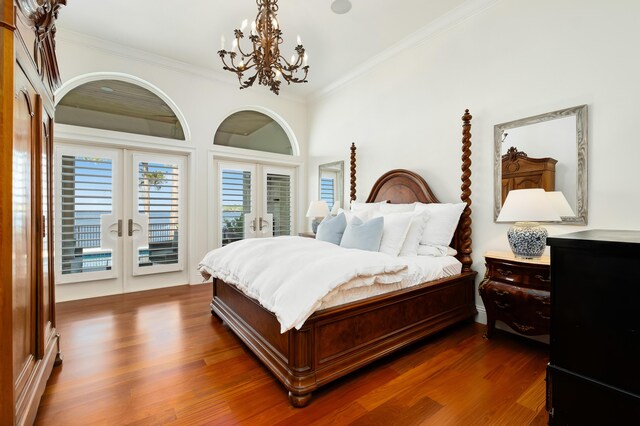 bedroom with crown molding, access to outside, an inviting chandelier, dark hardwood / wood-style floors, and french doors