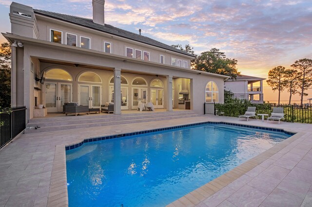 pool at dusk with a patio area and french doors