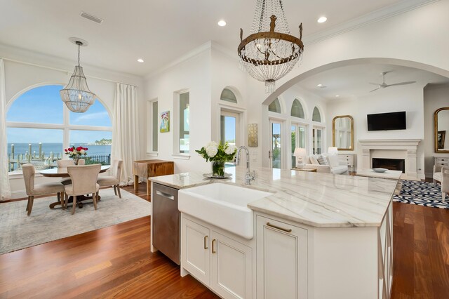 kitchen featuring ceiling fan with notable chandelier, hardwood / wood-style flooring, and a center island with sink