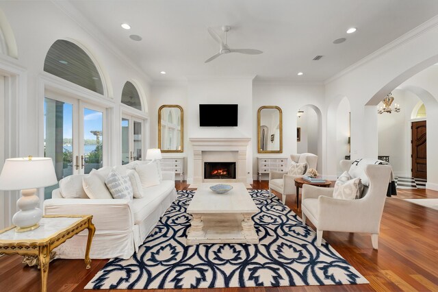 living room featuring crown molding, french doors, ceiling fan with notable chandelier, and hardwood / wood-style flooring