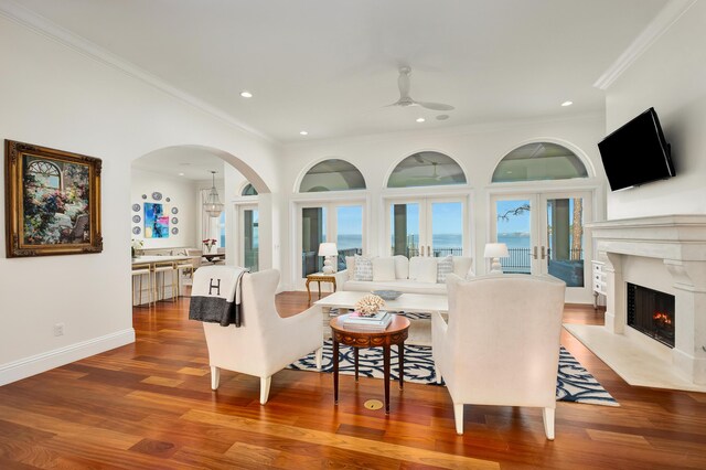 living room featuring crown molding, ceiling fan, a high end fireplace, and hardwood / wood-style floors