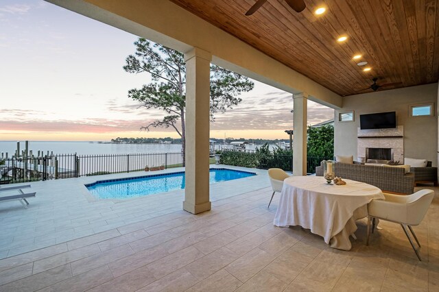 view of pool with a water view, a patio area, and a tiled fireplace