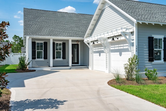 view of front facade featuring an attached garage, driveway, a shingled roof, and fence