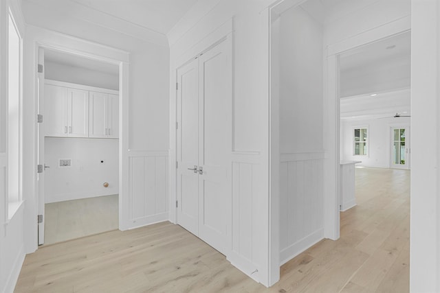 hallway featuring ornamental molding, light wood-type flooring, and wainscoting