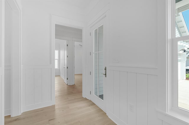 corridor with light wood-type flooring and wainscoting