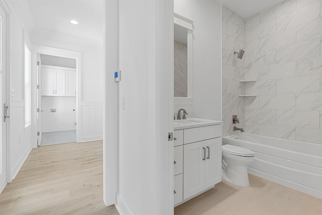 full bathroom featuring toilet, a wainscoted wall, wood finished floors, vanity, and washtub / shower combination