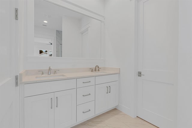 full bathroom featuring marble finish floor, a sink, baseboards, and double vanity