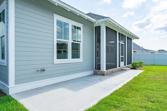 view of property exterior featuring a yard, a sunroom, fence, and a patio